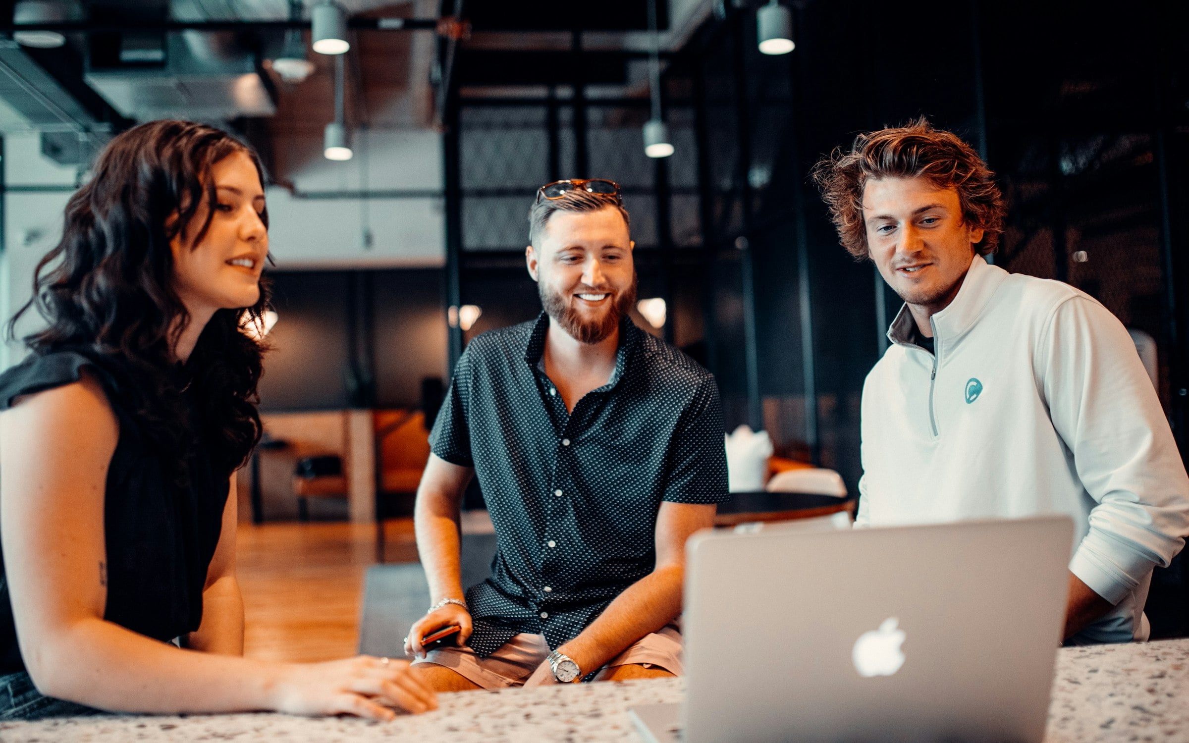 A team laughing together around a laptop