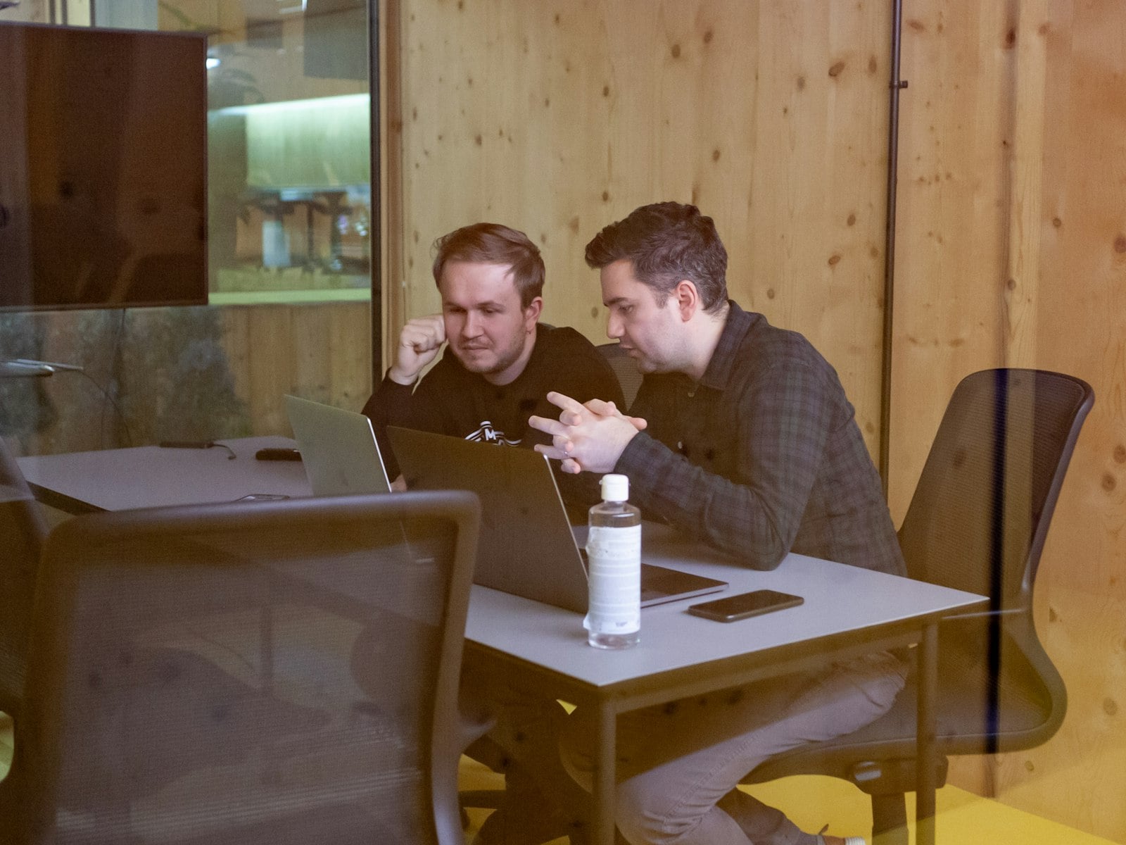 Two colleagues working through a plan at a wooden table